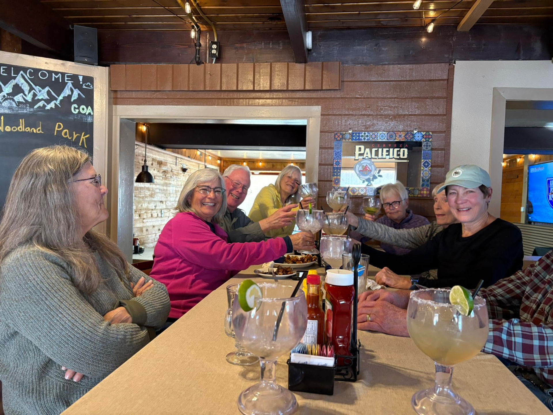 A table of friends leaning in to clink salt-rimmed margarita glasses together at the Vista Lounge bar