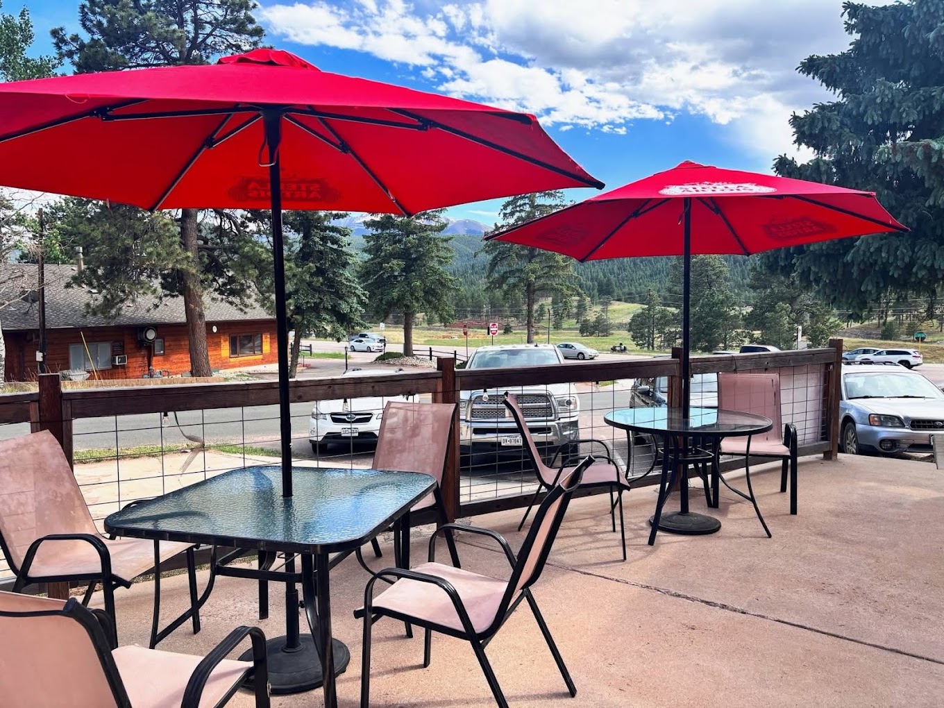 Outdoor patio at Vista Lounge with red umbrellas, wooden tables and mountain views