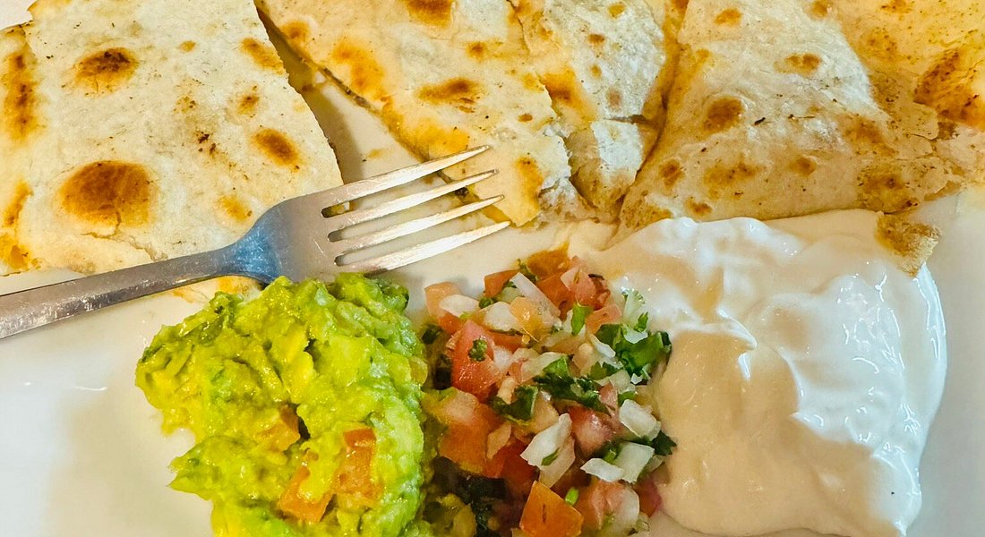 Grilled chicken quesadilla cut into wedges with guacamole, pico de gallo and sour cream on the side